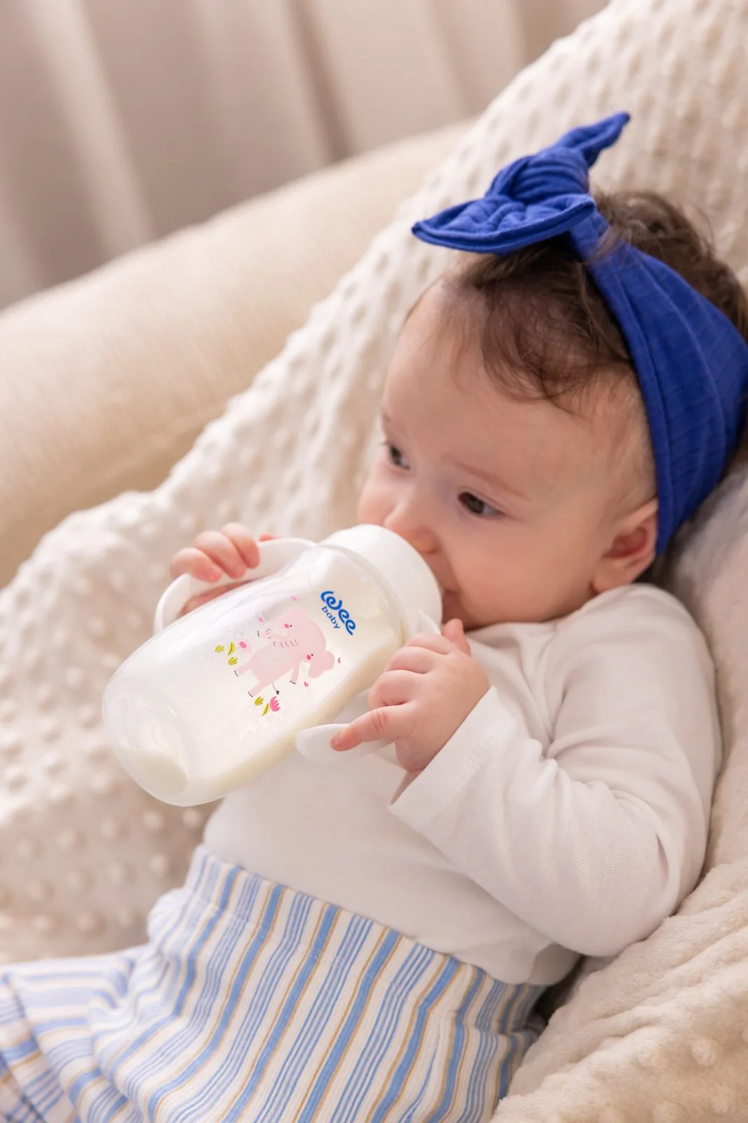 Ребёнок пьёт из бутылочки Wee Baby с ручками